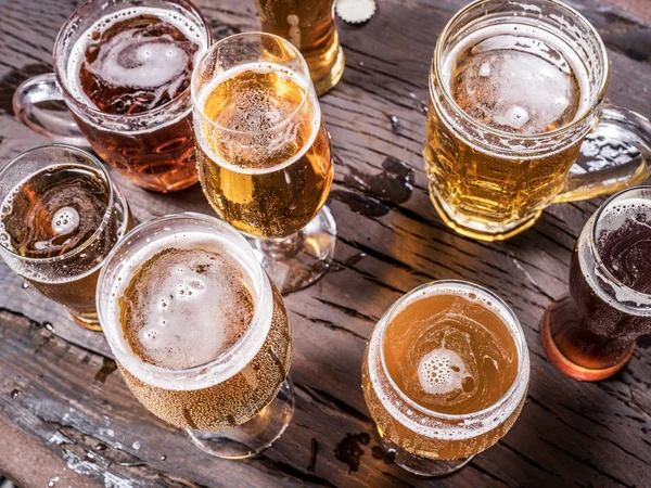 Různé sklenice piva na dřevěný stůl. — Stock fotografie