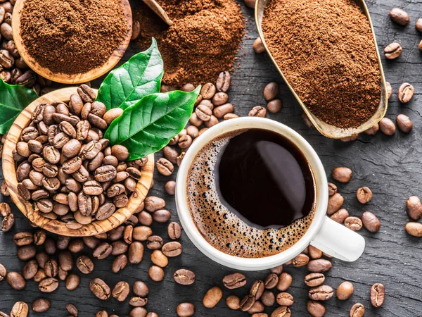 Gebrande koffiebonen, gemalen koffie en kopje koffie op houten — Stockfoto