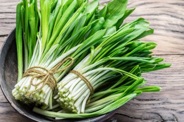 Ahşap masa üzerinde genç taze yabani sarımsak.