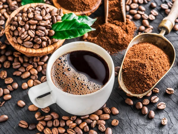 Смажені кавові зерна, мелена кава і чашка кави на дерев'яній — стокове фото