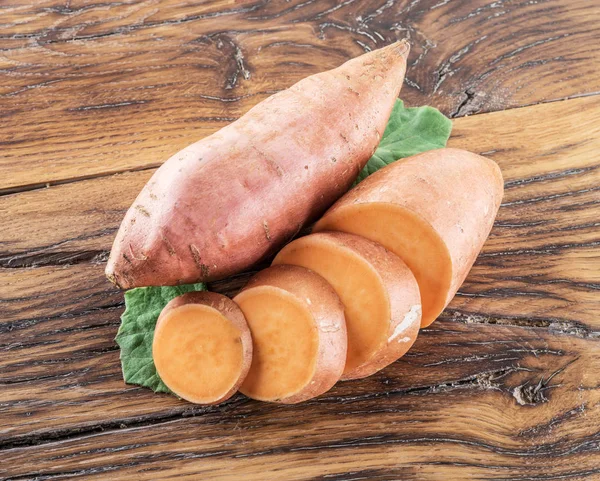 Sweet potatoes on the old wooden table. — Stock Photo, Image
