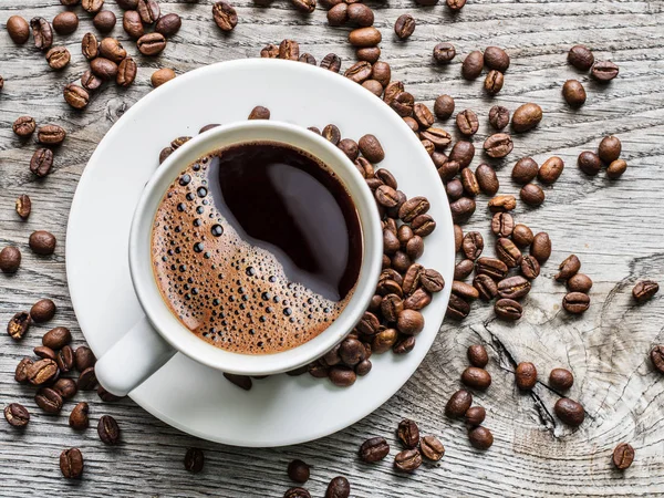 Kopp kaffe omgiven av kaffebönor. Ovanifrån. — Stockfoto