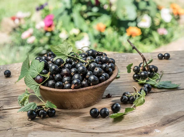 Zwarte bessen in de houten kom op de houten tafel. — Stockfoto