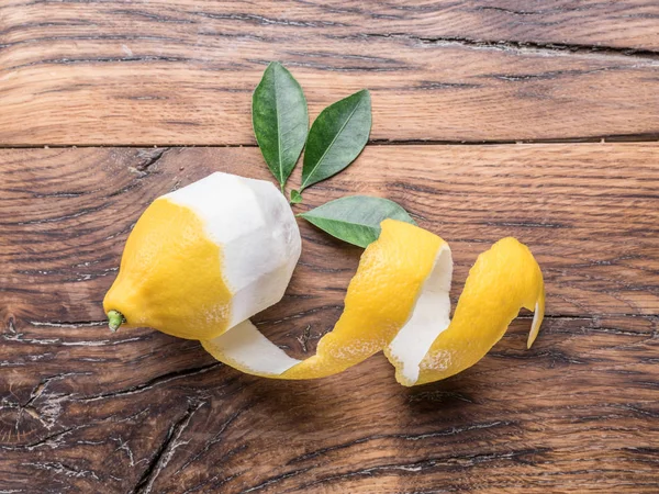 皮をむいたレモンと木製の背景にレモンの葉。トップ ビュー. — ストック写真