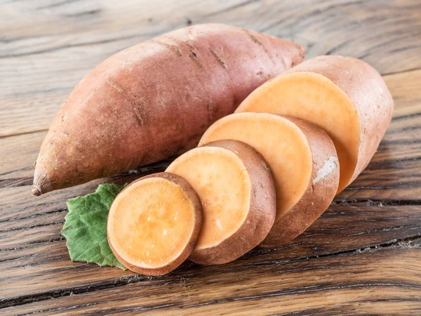 Sladké brambory na dřevěném stole. — Stock fotografie