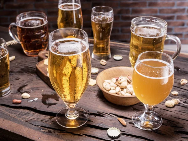 Copos de cerveja e lanches na mesa de madeira . — Fotografia de Stock