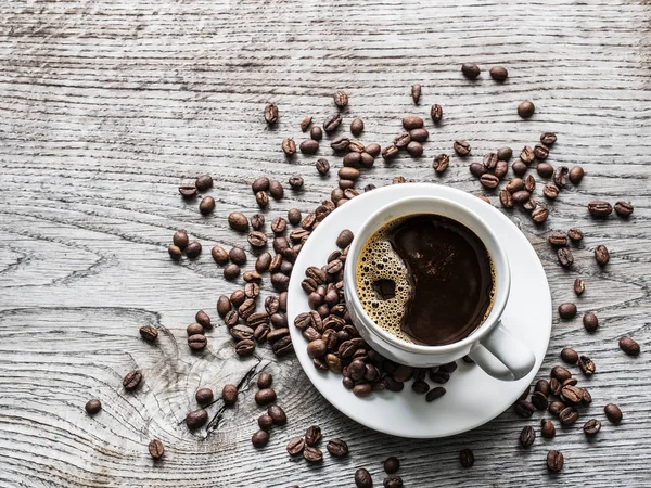 Kopp kaffe omgiven av kaffebönor. Ovanifrån. — Stockfoto