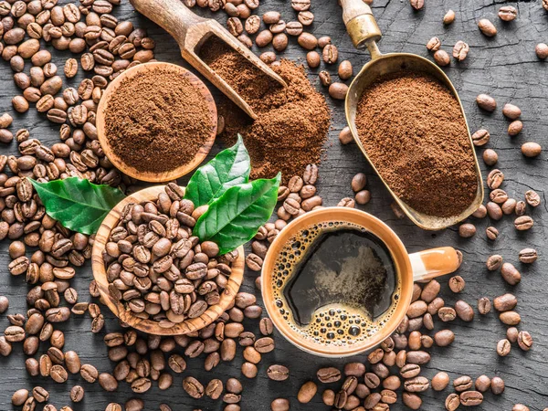 Grãos de café torrados, café moído e xícara de café em madeira — Fotografia de Stock