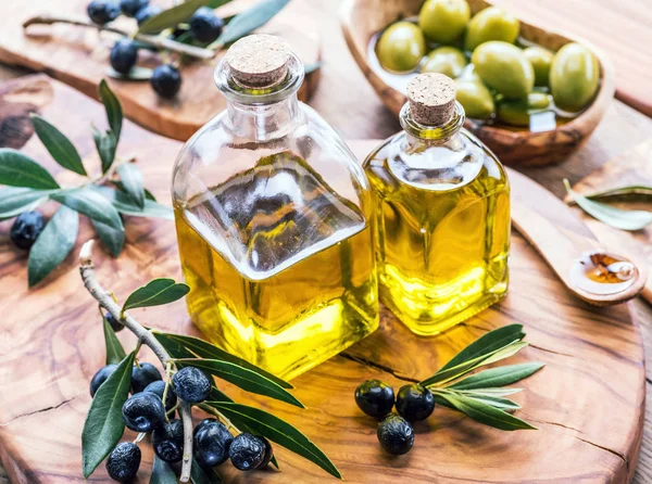 Aceite de oliva y bayas están en la bandeja de madera de oliva . —  Fotos de Stock