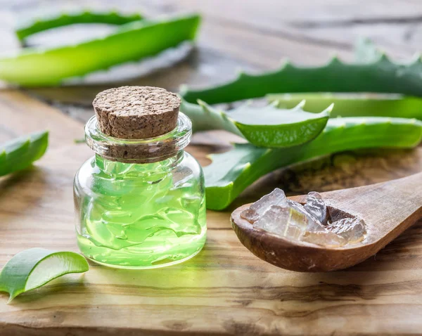 Gel de aloés fresco no frasco cosmético e colher na mesa de madeira . — Fotografia de Stock