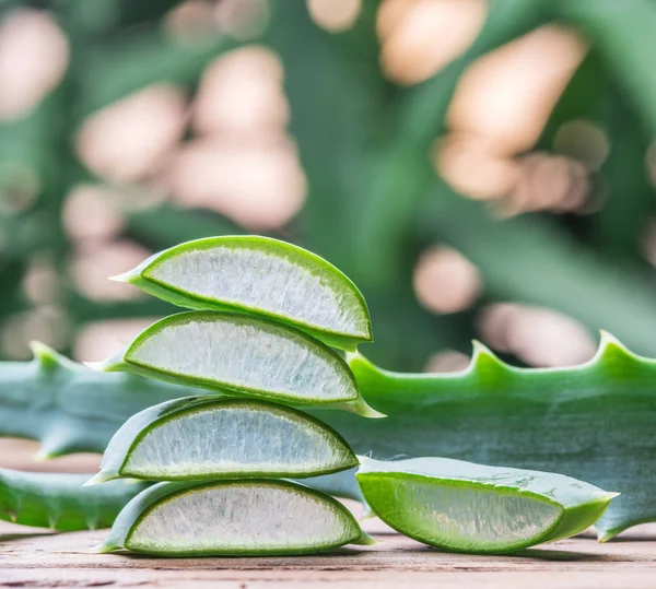 Hojas de aloe frescas y gel de aloe en el frasco cosmético en la pestaña de madera —  Fotos de Stock