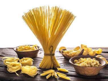 Different pasta types on wooden table. White background. clipart
