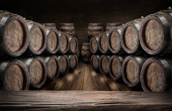 Old wooden table top and oak wine barrels at the background. — Stock Photo, Image