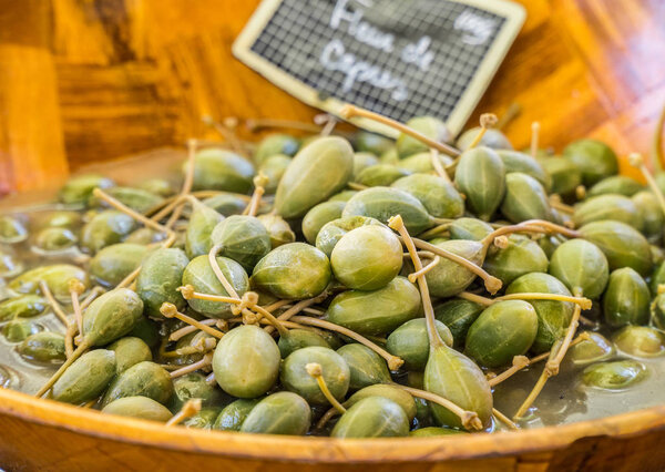 Pickled flower buds of caper or capers in the wooden dish.