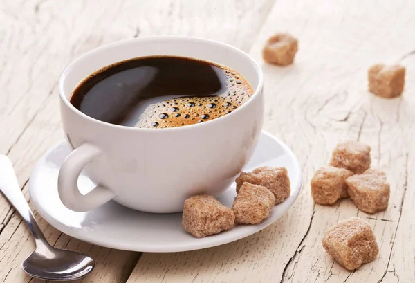 Tasse Kaffee und braune Zuckerwürfel auf dem Holztisch. — Stockfoto