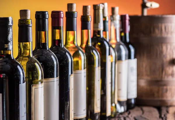 Botellas de vino en fila y barril de vino de roble . — Foto de Stock