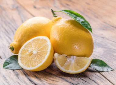 Olgun limon limon ile eski ahşap masanın üzerine bırakır. Yakın çekim.