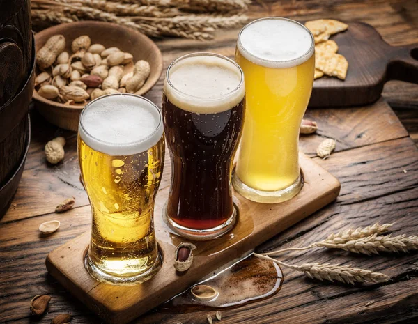 Copos de cerveja e lanches na mesa de madeira . — Fotografia de Stock