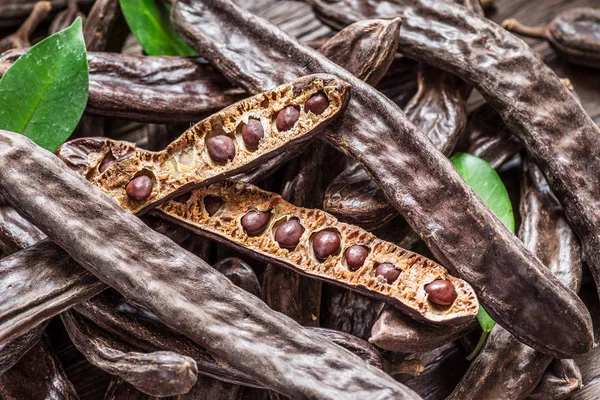 Carob pods och carob bönor på tabellen trä. — Stockfoto