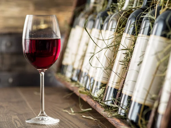 Copo de vinho tinto e garrafas de vinho no fundo . — Fotografia de Stock