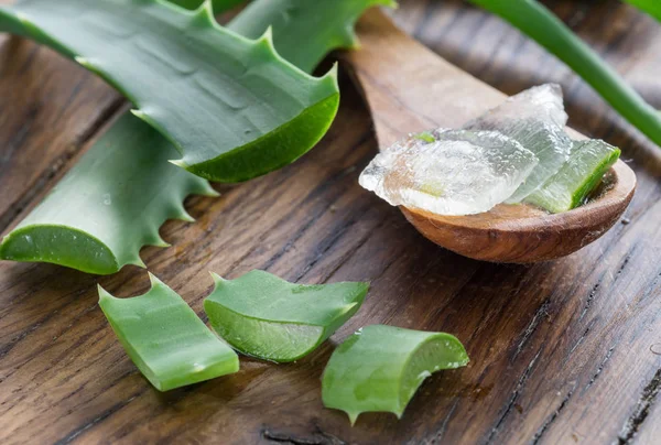 Fresh aloe leaves and aloe gel in the wooden spoon on the table. — Stock Photo, Image