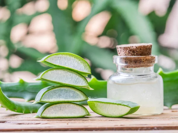 Hojas de aloe frescas y gel de aloe en el frasco cosmético en la pestaña de madera — Foto de Stock