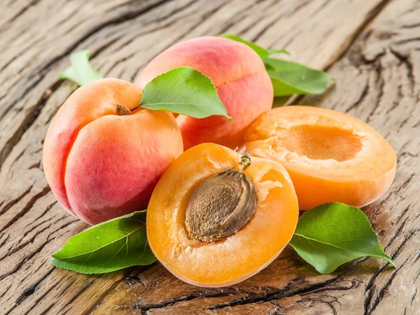 Apricots and its cross-section on the old wooden table. — Stock Photo, Image