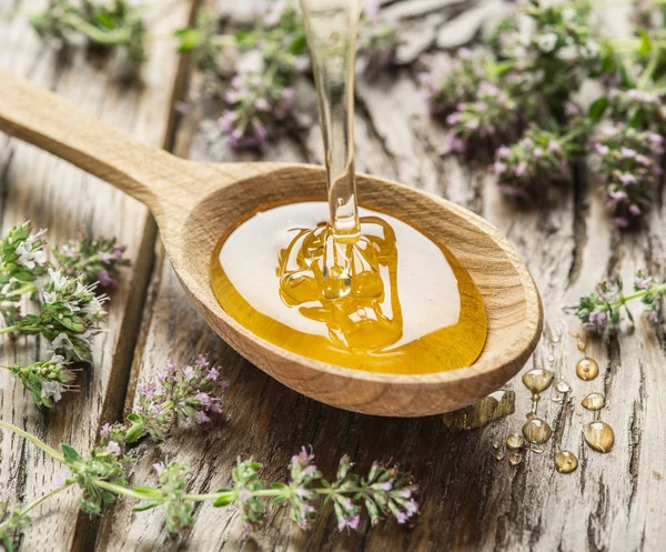 Miel à base de plantes versé dans la cuillère en bois. Cuillère est sur vieux bois — Photo