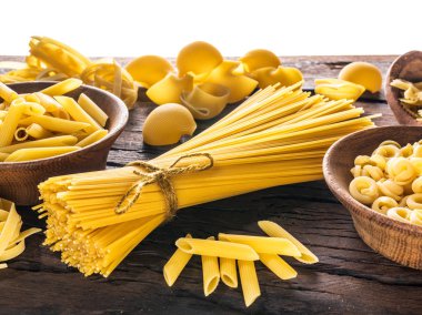 Different  pasta types  in wooden spoons on the table. clipart