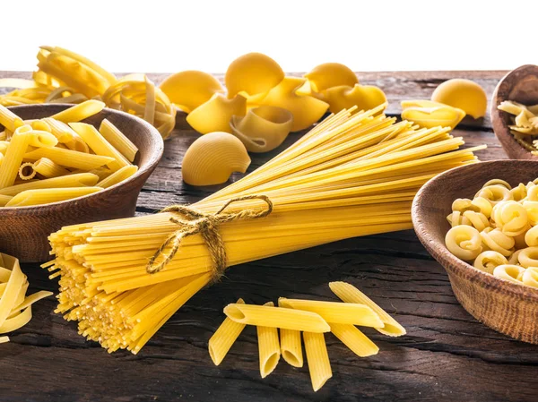 Diversi tipi di pasta in cucchiai di legno sul tavolo. — Foto Stock