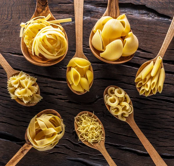 Diversi tipi di pasta in cucchiai di legno sul tavolo. Vista dall'alto. — Foto Stock