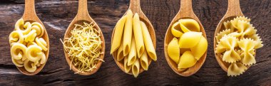 Masadaki tahta kaşıklarda farklı makarna tipleri. Üst görünüm.