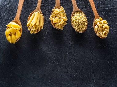 Masadaki tahta kaşıklarda farklı makarna tipleri. Üst görünüm.