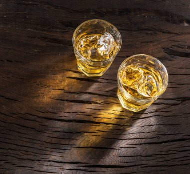 Whiskey glasses or glasses of whiskey with ice cubes on the wood clipart