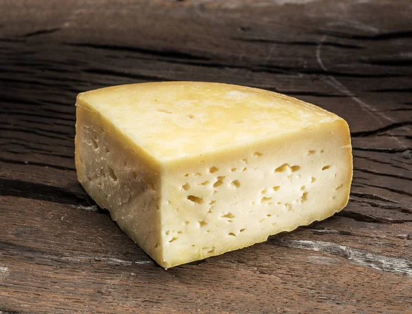Kawałek sera w domu na podłoże drewniane. — Zdjęcie stockowe