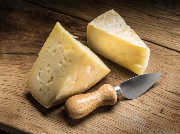 Stukken van zelfgemaakte kaas op de houten achtergrond. — Stockfoto