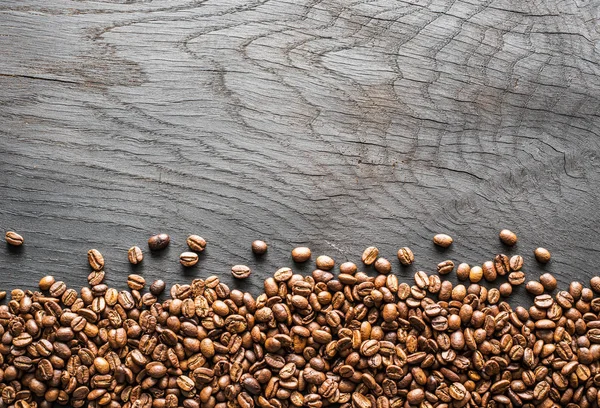 Pieczone ziarna kawy na drewnianym stole. Widok z góry. — Zdjęcie stockowe