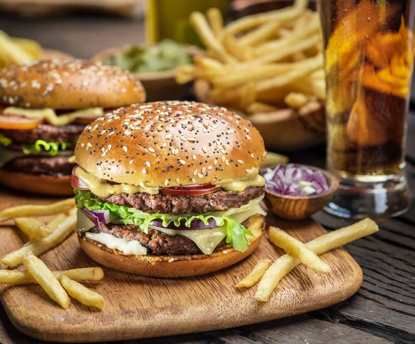 Hamburguesas y papas fritas en la bandeja de madera. — Foto de Stock