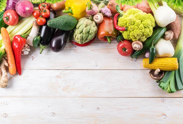 Різні барвисті овочі розташовані як рамка. Дерев'яний ремінь — стокове фото