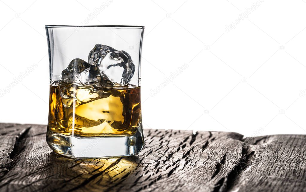 Whiskey glass or glass of whiskey with ice cubes on the table at