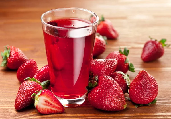 Glas jordgubbsjuice och jordgubbar på träbord. — Stockfoto
