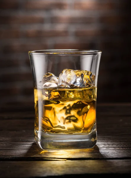 Whiskey glass or glass of whiskey with ice cubes on the wooden b — Stock Photo, Image