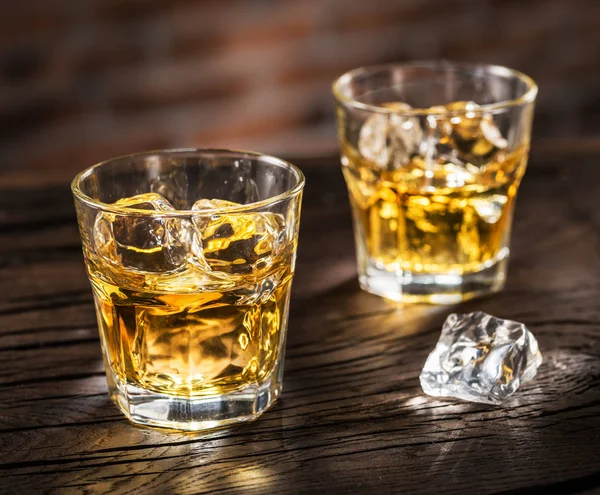 Whiskey glasses or glasses of whiskey with ice cubes on the wood — Stock Photo, Image