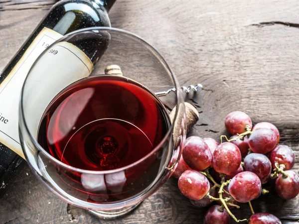Sklenice na víno, láhev vína a hroznů na dřevěné pozadí. Ta vína — Stock fotografie
