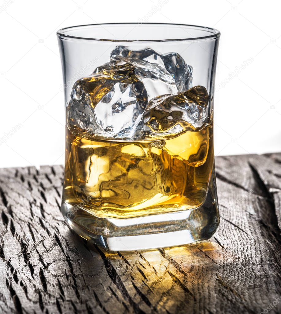 Whiskey glass or glass of whiskey with ice cubes on the table at