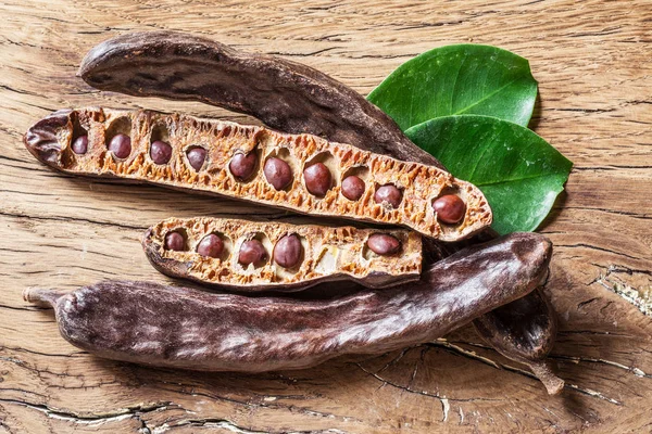 Carob pods och carob bönor på tabellen trä. — Stockfoto