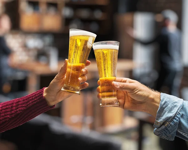 Beer glasses raised in a toast. Close-up hands with glasses.