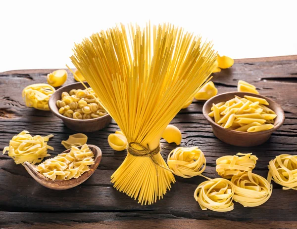 Verschillende pasta soorten op houten tafel. Witte achtergrond. — Stockfoto