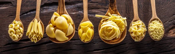 Diferentes tipos de pasta en cucharas de madera sobre la mesa. Vista superior. —  Fotos de Stock