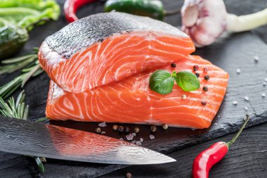 Otlar, baharatlar ile siyah kesme tahtası üzerinde taze somon fileto